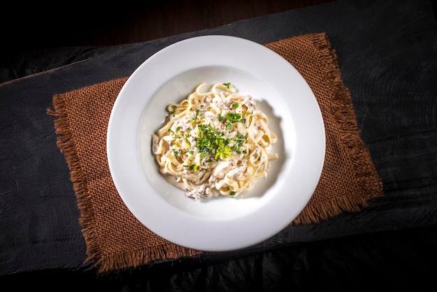 Meat tagliatelli on brown cloth and black wood top view