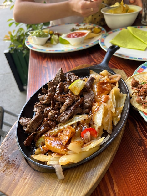 Meat with cabbage in a pan on a stand stands on a table in a restaurant