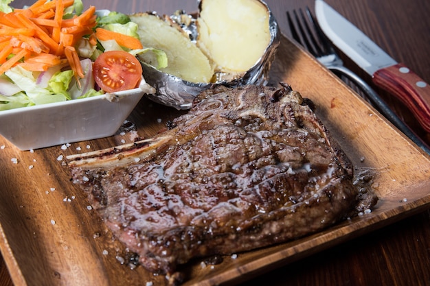 Meat with vegetables on a wooden plate