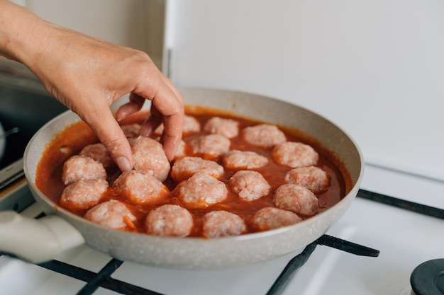 Meatballs cooking process in a pan at home Beef chicken and pork meat food recipe in tomato sauce