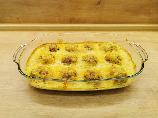 Meatballs in a creamy sauce baked in the oven with cheese in a large plate