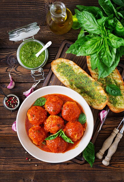 Photo meatballs in tomato sauce and toast with basil pesto.