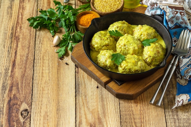 Meatballs with bulgur in sour cream and turmeric sauce in a castiron skillet Copy space