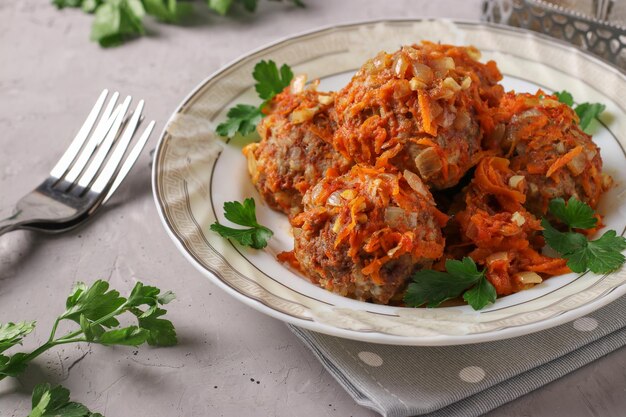 Meatballs with rice and minced beef in tomato sauce in plate on light gray background