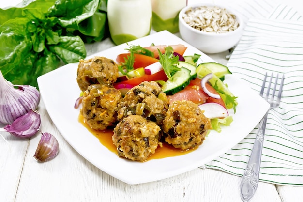 Meatballs with spinach and oatmeal on wooden table