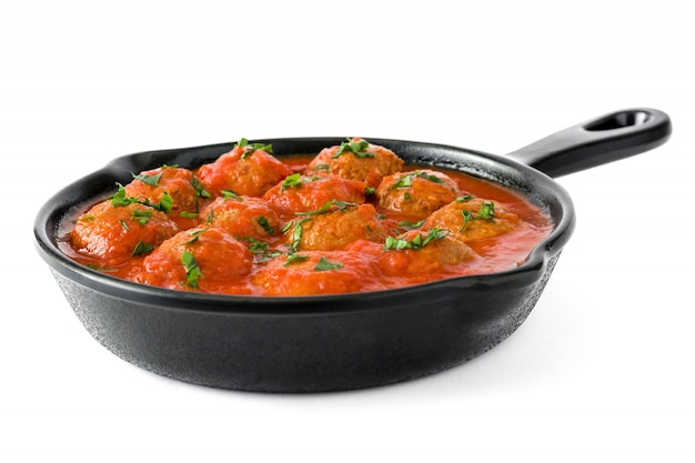 Meatballs with tomato sauce in iron frying pan isolated on white