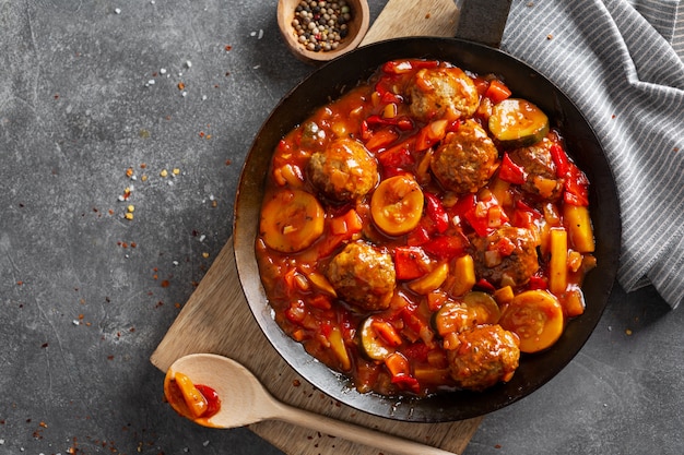 Meatballs with vegetables and sauce made in pan and served on table.