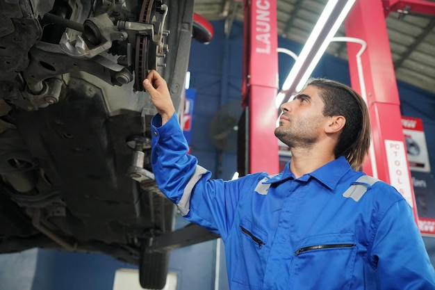 Mechanic in blue overalls checking serviceability of car engine