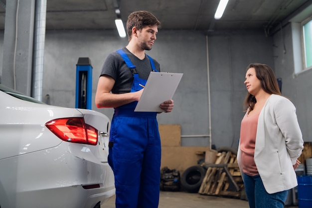 Mechanic in a car service talking with a customer about a car repair