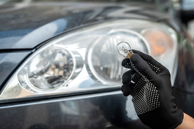 Mechanic change low-beam or high-beam light bulb in his car, close up