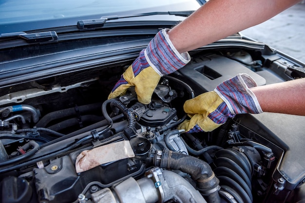 Mechanic examining car engine under hood close up