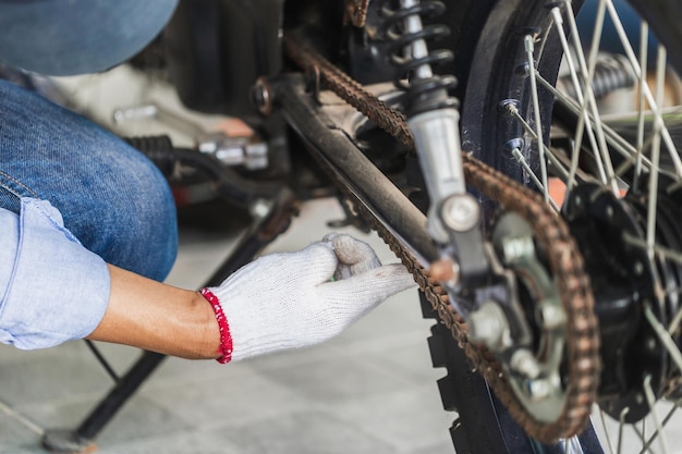 Mechanic fixing motorbike in workshop garage Man repairing motorcycle in repair shop Repairing and maintenance concepts