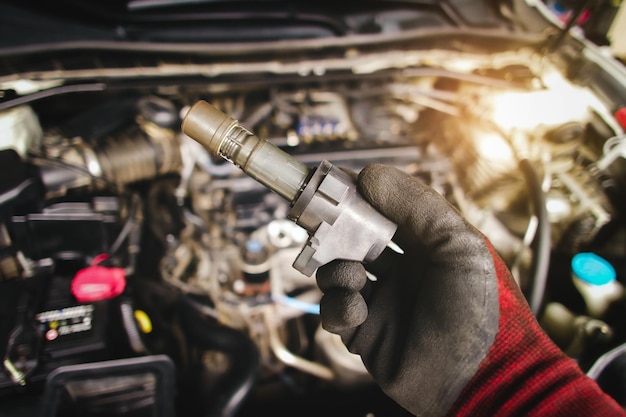 A mechanic hand holds an ignition coil for a spark plug in an automobile engine isolated object on blurred background