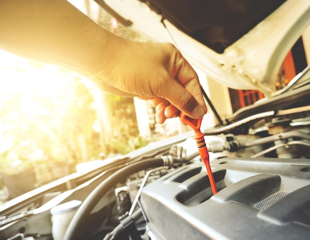 Mechanic hand was pulling oil dipstick to lube level checking of engine car