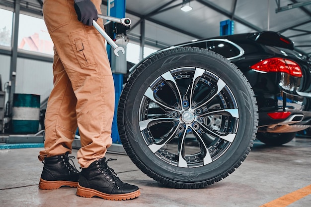 Mechanic holding a tire at the repair garage Replacement of winter and summer tires Cropped photo