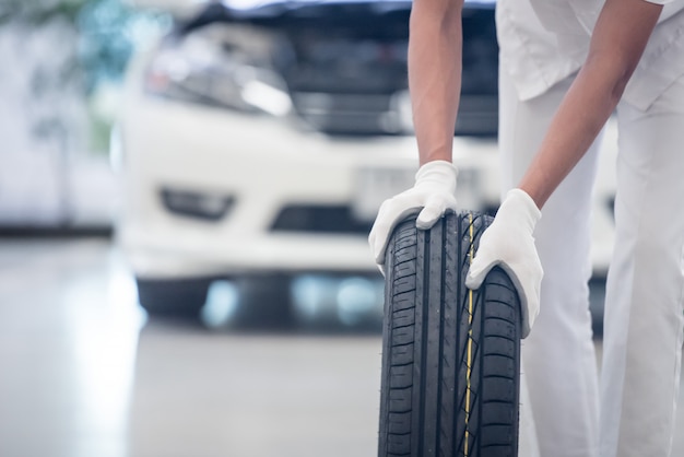 Mechanic holding a tire tire at the repair garage. replacement of winter and summer tires.