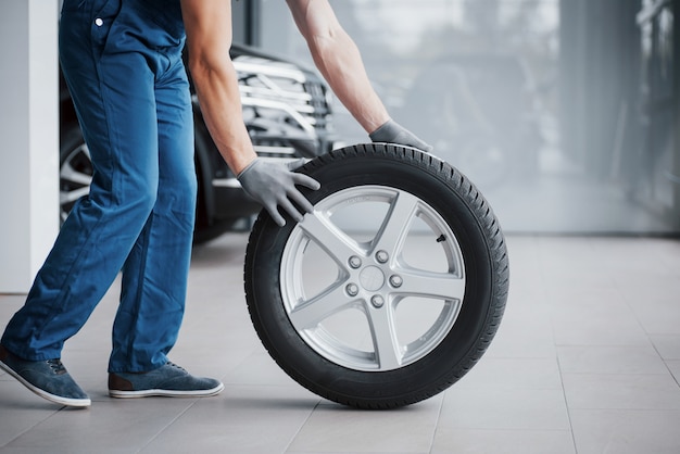 Mechanic holding a tire tire at the repair garage. replacement of winter and summer tires