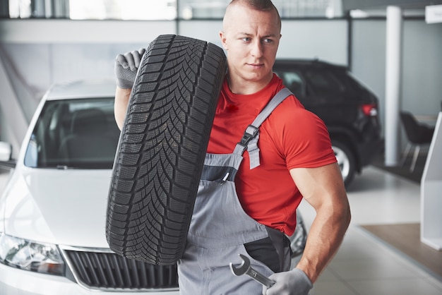 Photo mechanic holding a tire tire at the repair garage. replacement of winter and summer tires.