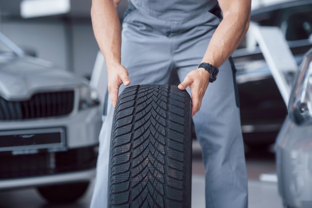 Mechanic holding a tire tire at the repair garage. replacement of winter and summer tires