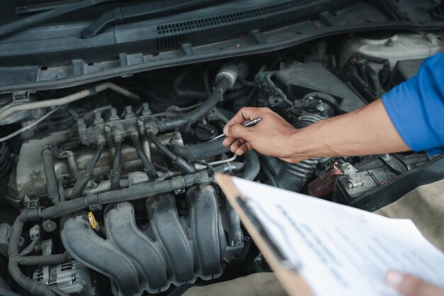 The mechanic is repairing the engine A car repair worker is inspecting a car A car mechanic is looking at what is the problem with the engine in the garage