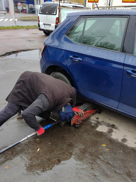 The mechanic looks under the car to lift it on a jack and replace the wheel