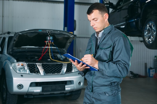 Mechanic maintaining car record on clipboard at the repair shop.