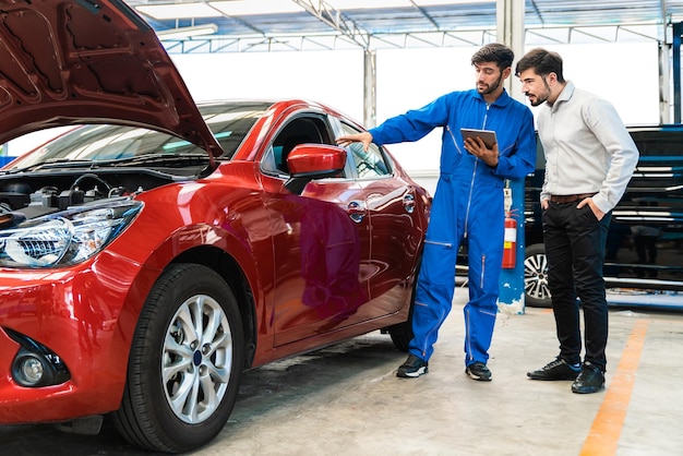 Mechanic man shows the car report on a digital tablet to the Middle East customer at the garage