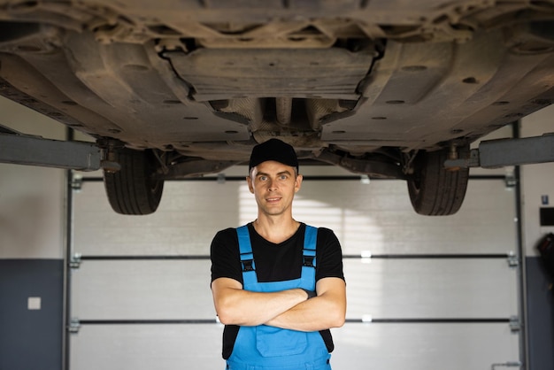 Mechanic man standing in front of the garage joyful young bearded man motor mechanic in overalls