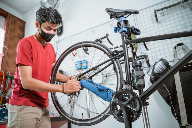 A mechanic in mask working tighten the bicycle axle with a wrench