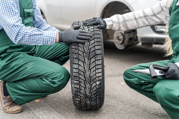 Mechanic posing with spare wheel on roadside