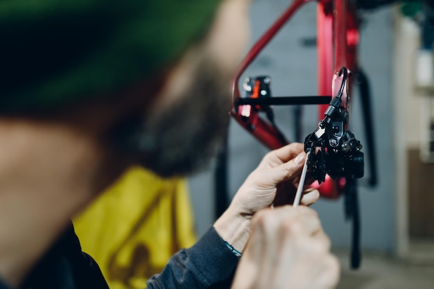 Mechanic repairman assembling brake cable custom bicycle in workshop