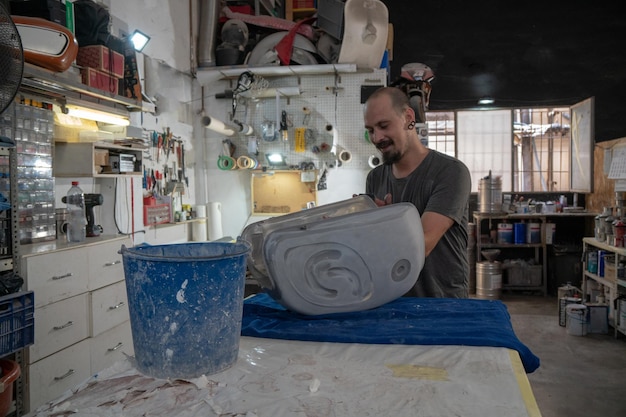 Mechanic sanding a motorcycle tank