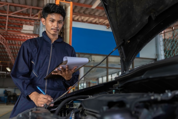 A mechanic service car in garage is paper check a list cars.