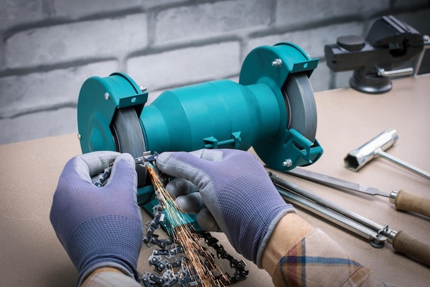 Mechanic sharpening a chainsaw chain with a electric sharpener