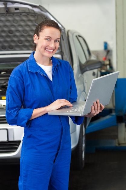 Mechanic smiling at the camera holding laptop