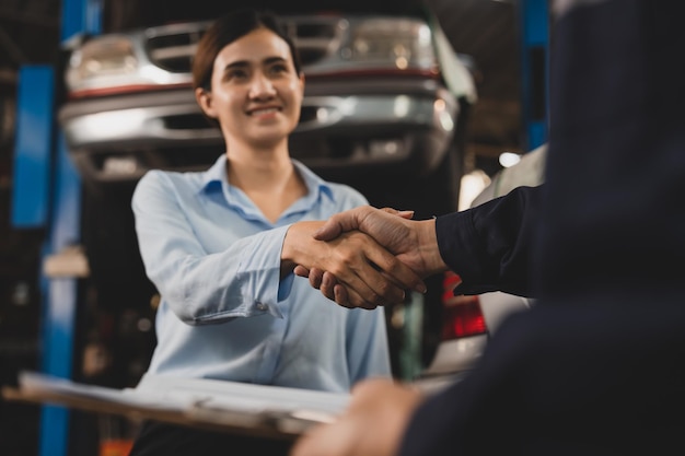 Mechanic technician man shaking hands with customer after finish checking the car at the garage two people handshake for a working job at professional auto car repair service center