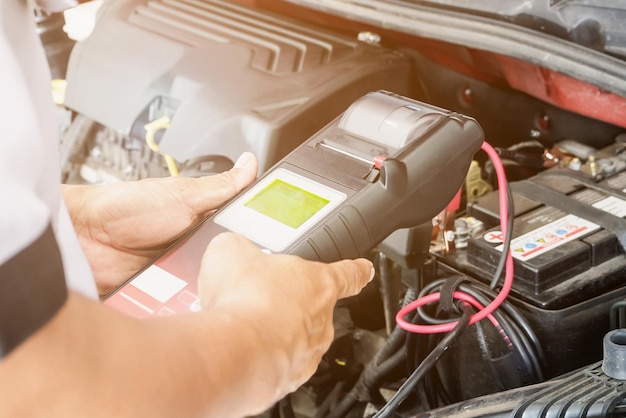 Mechanic use voltmeter checking voltage of car battery in car service centre