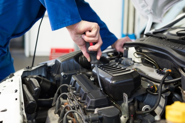 Mechanic using screwdriver on engine