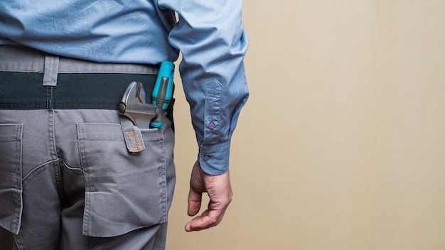 Mechanic wearing a gray uniform with repairing tools on the pockets