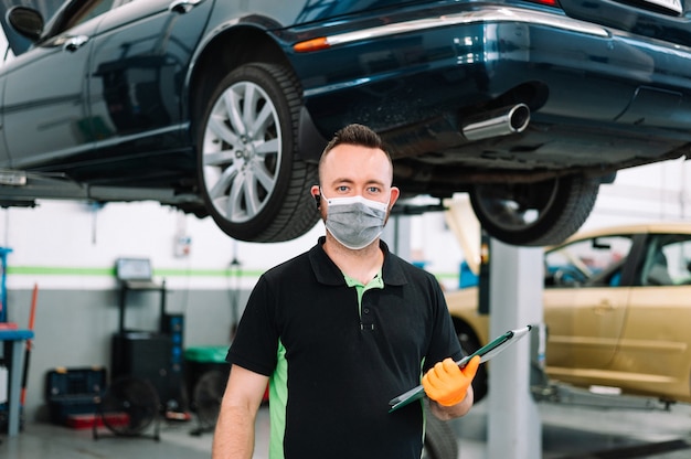 mechanic wearing surgical mask holding a clipboard working in garage Repair service