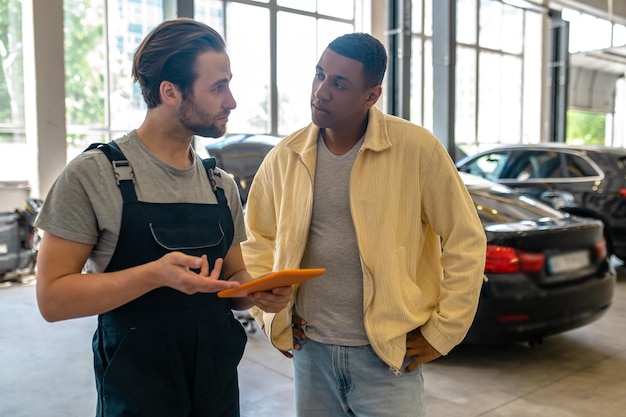 Mechanic with clipboard asking thoughtful customer