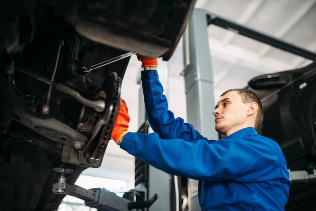 Mechanic with wrench repairs the suspension of car