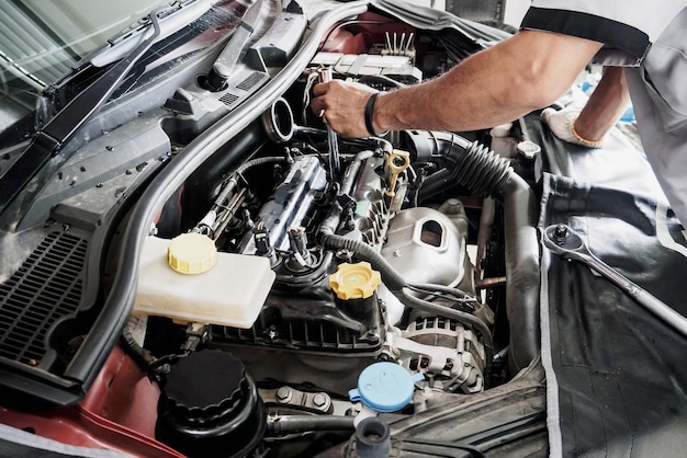 Mechanic with wrench working and repair car engine in car service centre