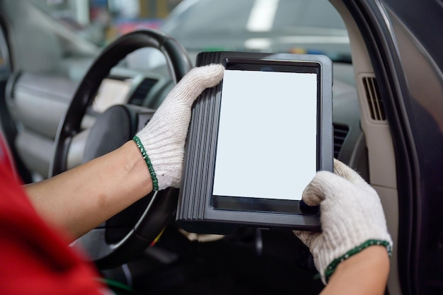 The mechanic works at the car service center Use the scanner to diagnose vehicle problems using an electronic OBD and OBD2 device on your tablet