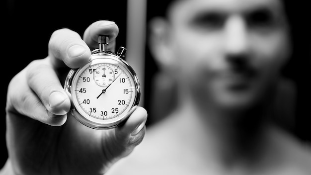 Mechanical stopwatch in a hand. Man athlete with a clock face. Fitness and sport concept