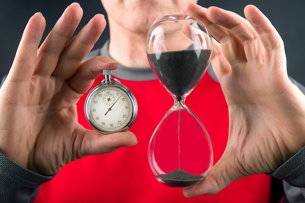 Mechanical stopwatch and hourglass in hand Time part precision Measuring the speed interval with a watch