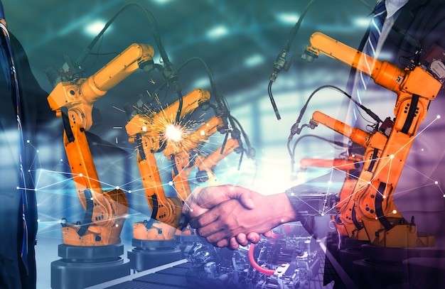 Mechanized industry robot arm and business handshake double exposure