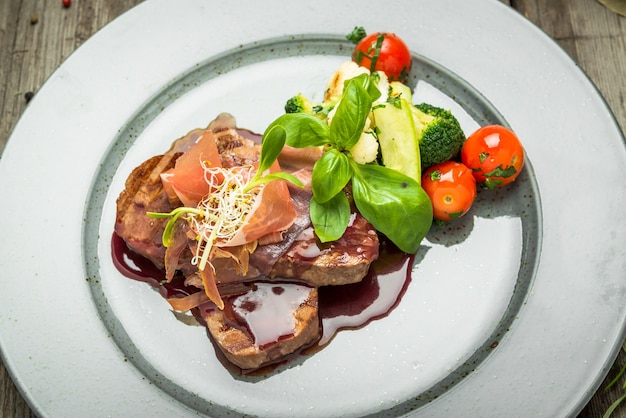 Medallions of veal, with sauce on a plate. Wooden table