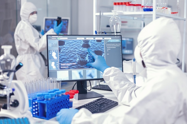 Medic and nurse dressed in protection suit against coronavirus egineering vaccine. Lab engineers conducting experiment for vaccine development against covid19 virus