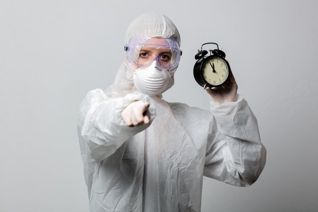 Medic in protection clothes holds alarm clock